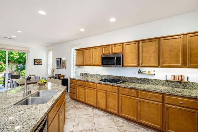 kitchen featuring light tile patterned floors, sink, light stone counters, and stainless steel appliances