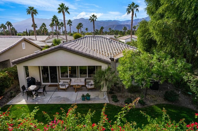 back of property featuring a lawn, a patio area, and a mountain view