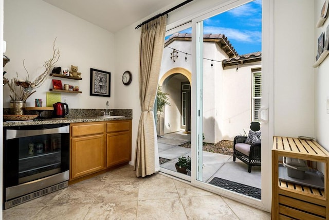 interior space with sink, dark stone counters, and beverage cooler