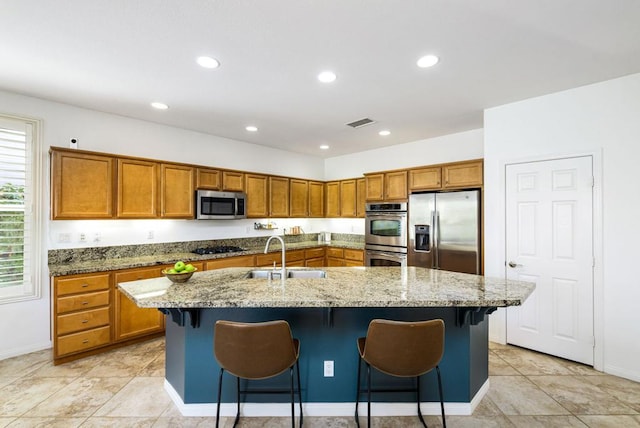 kitchen featuring a kitchen bar, sink, a center island with sink, and stainless steel appliances