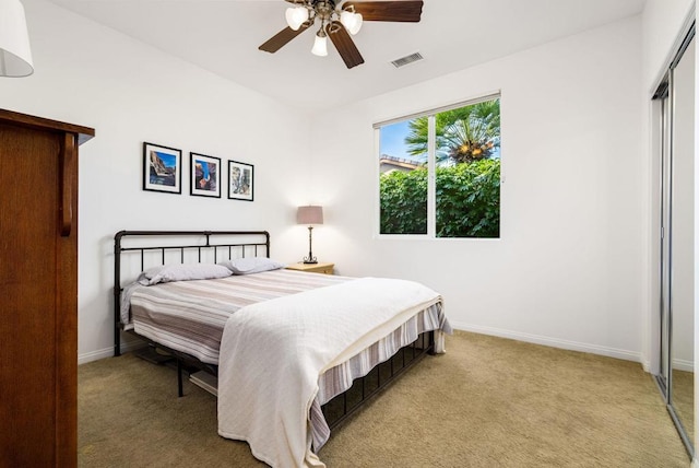 carpeted bedroom featuring ceiling fan and a closet