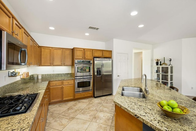 kitchen featuring light tile patterned flooring, stainless steel appliances, light stone counters, and sink