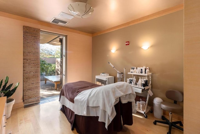 bedroom with crown molding, light hardwood / wood-style floors, and access to outside