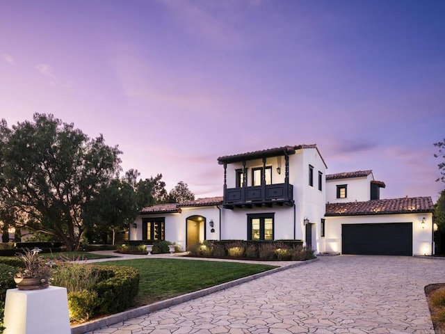 mediterranean / spanish home featuring a yard, a balcony, and a garage