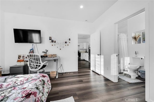 bedroom with dark wood-type flooring and connected bathroom