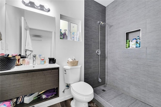 bathroom with toilet, vanity, and a tile shower