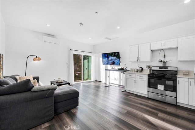 kitchen with a wall mounted AC, white cabinets, dark hardwood / wood-style flooring, and gas stove