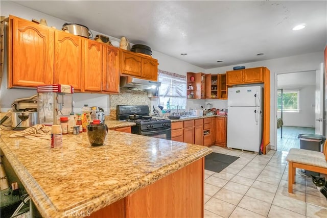 kitchen featuring kitchen peninsula, black range with gas cooktop, sink, light tile patterned floors, and white fridge