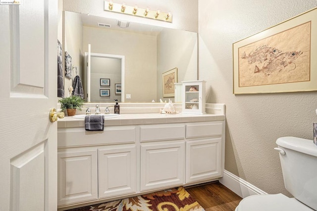 bathroom with vanity, toilet, and wood-type flooring