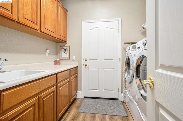 laundry area featuring separate washer and dryer, sink, cabinets, and light wood-type flooring