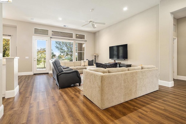 living room with dark wood-type flooring, ceiling fan, and a healthy amount of sunlight