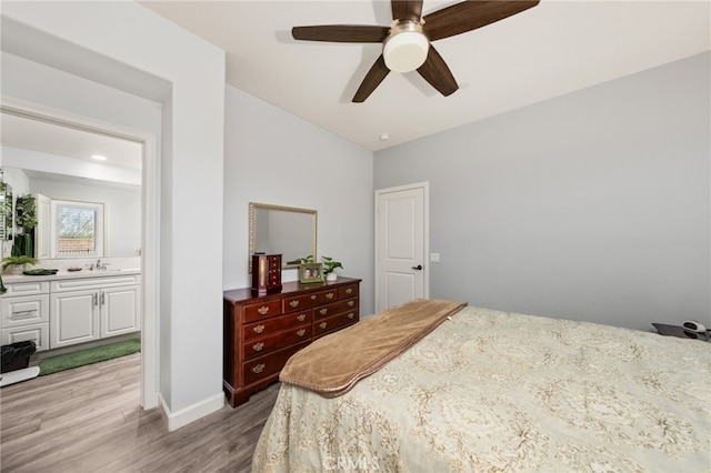 bedroom with ceiling fan, sink, light wood-type flooring, and ensuite bath