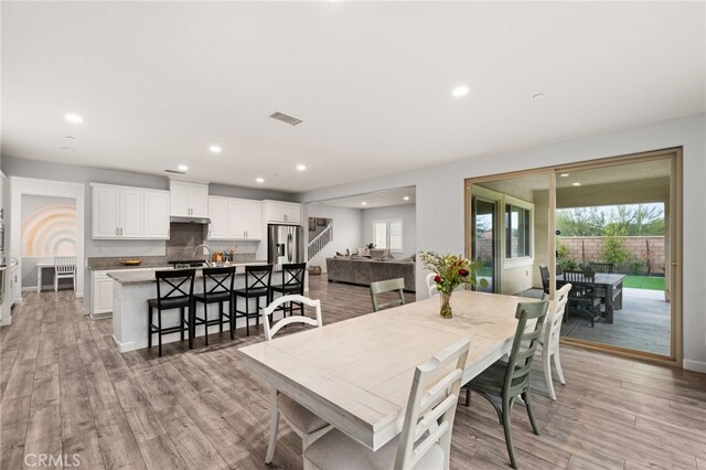 dining space with sink, light hardwood / wood-style floors, and a healthy amount of sunlight