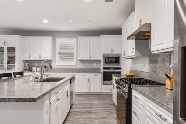 kitchen with dark stone countertops, appliances with stainless steel finishes, white cabinetry, and sink