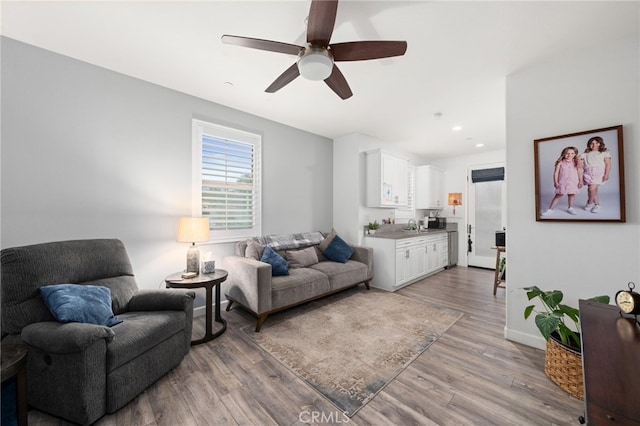 living room featuring ceiling fan, light hardwood / wood-style flooring, and sink