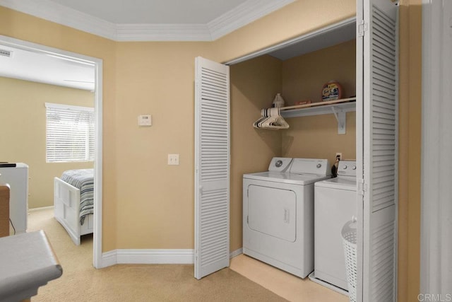 clothes washing area with light colored carpet, ornamental molding, and washing machine and clothes dryer