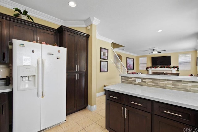 kitchen featuring dark brown cabinetry, ceiling fan, white fridge with ice dispenser, tasteful backsplash, and crown molding