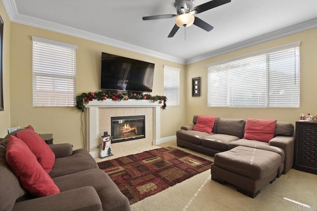 carpeted living room with ceiling fan, ornamental molding, and a tile fireplace