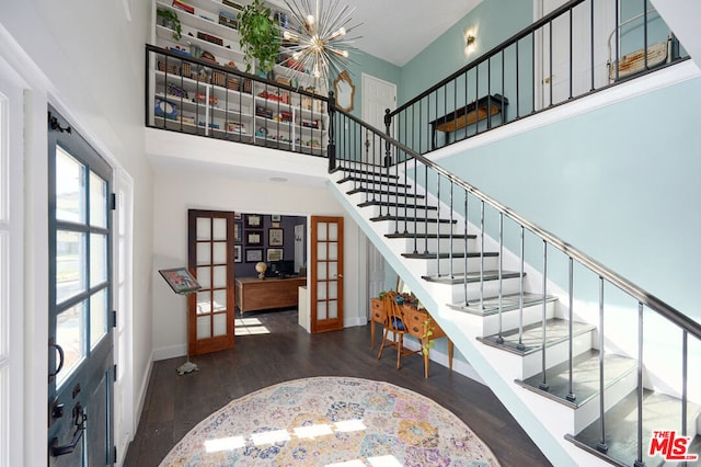 stairway featuring french doors, a high ceiling, and hardwood / wood-style flooring