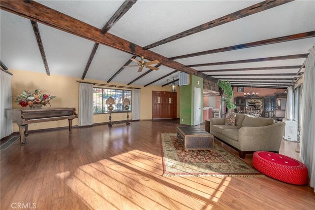 living room featuring ceiling fan with notable chandelier, wood-type flooring, and vaulted ceiling with beams