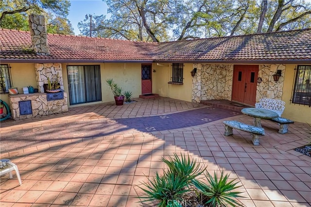 exterior space with stucco siding, a patio, and a tiled roof