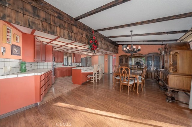 kitchen featuring an inviting chandelier, tile countertops, light wood-style floors, and stainless steel refrigerator with ice dispenser