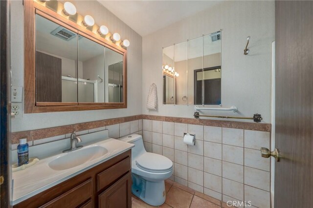 bathroom featuring vanity, tile walls, tile patterned flooring, toilet, and a shower with shower door