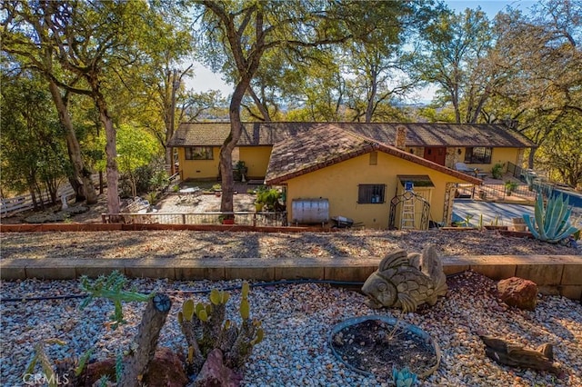 back of property with stucco siding, heating fuel, and fence