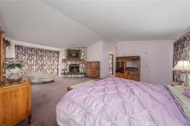 bedroom featuring a stone fireplace, lofted ceiling, visible vents, and carpet floors