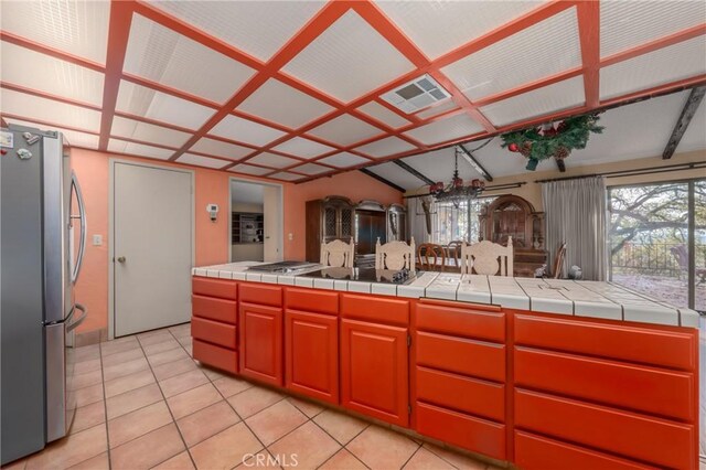 kitchen with tile countertops, light tile patterned floors, lofted ceiling, and appliances with stainless steel finishes