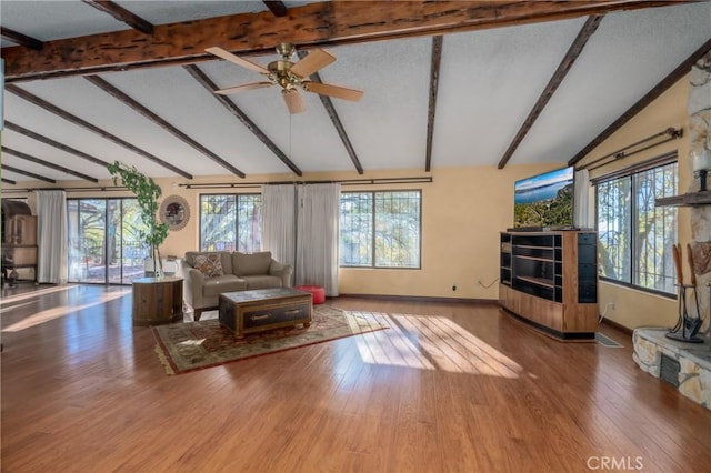 living area featuring wood finished floors, baseboards, lofted ceiling with beams, ceiling fan, and a textured ceiling
