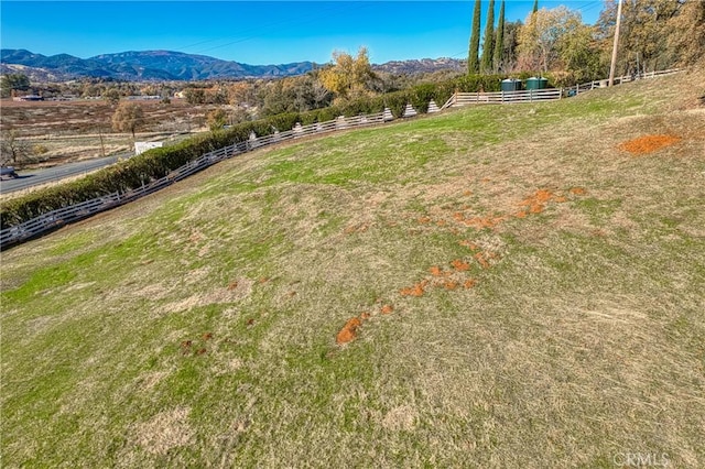 view of yard featuring a mountain view, a rural view, and fence