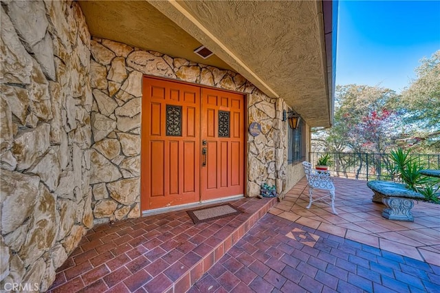 entrance to property featuring visible vents and stone siding