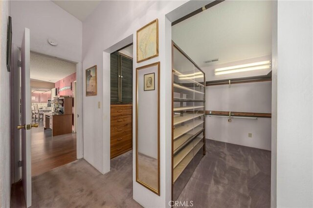 walk in closet featuring dark colored carpet