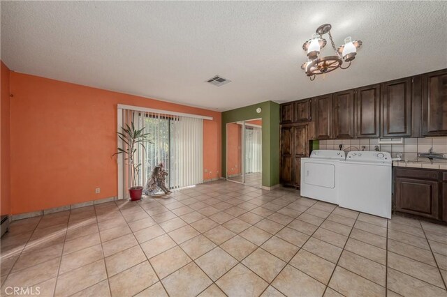 laundry area with a chandelier, washer and clothes dryer, light tile patterned flooring, and cabinets