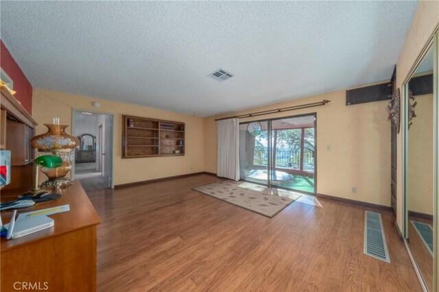 unfurnished living room featuring hardwood / wood-style floors and a textured ceiling