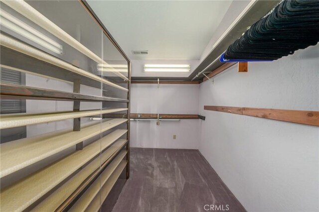 walk in closet featuring dark colored carpet