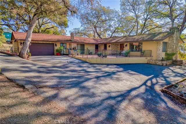 single story home with stucco siding, driveway, stone siding, fence, and an attached garage