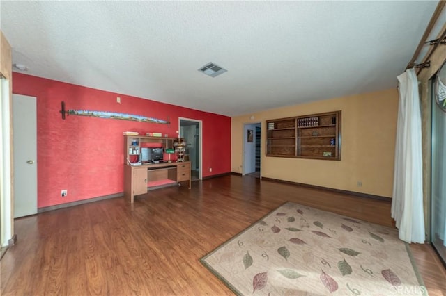 living room featuring baseboards, wood finished floors, visible vents, and a textured ceiling