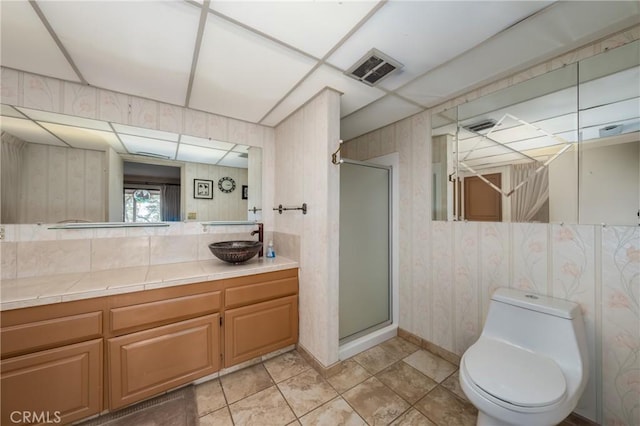 bathroom featuring visible vents, wallpapered walls, toilet, a stall shower, and vanity
