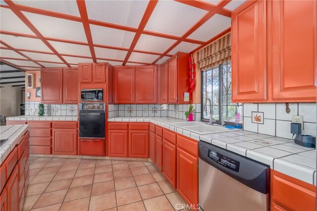 kitchen featuring appliances with stainless steel finishes, backsplash, sink, light tile patterned floors, and tile countertops