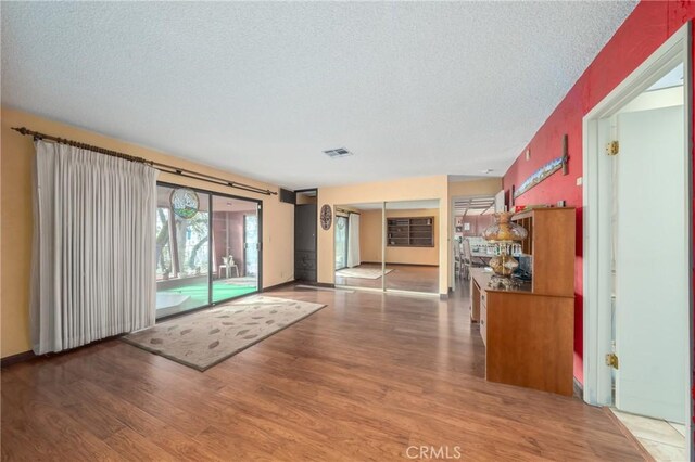 interior space featuring visible vents, a textured ceiling, and wood finished floors