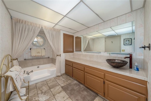 full bathroom featuring vanity, a washtub, a drop ceiling, and wallpapered walls