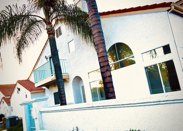 view of side of property featuring cooling unit and a balcony