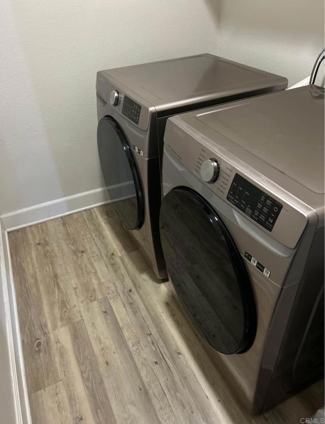 laundry room with washer and clothes dryer and light hardwood / wood-style flooring