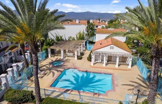 view of swimming pool with a pergola, a mountain view, a patio, and a hot tub