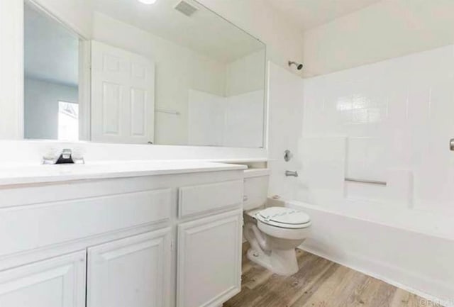 full bathroom featuring hardwood / wood-style floors, vanity, shower / bath combination, and toilet