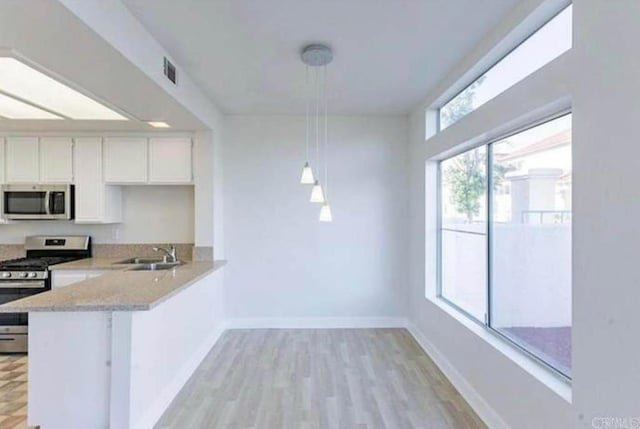 kitchen featuring white cabinets, sink, hanging light fixtures, appliances with stainless steel finishes, and kitchen peninsula