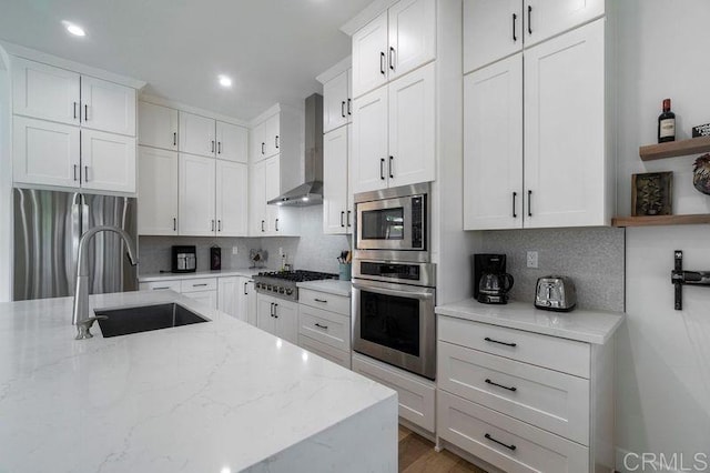 kitchen with decorative backsplash, sink, wall chimney exhaust hood, and appliances with stainless steel finishes