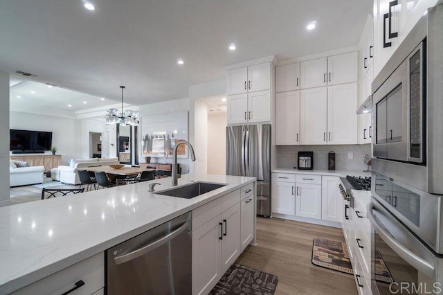 kitchen with light stone counters, sink, white cabinets, and stainless steel appliances